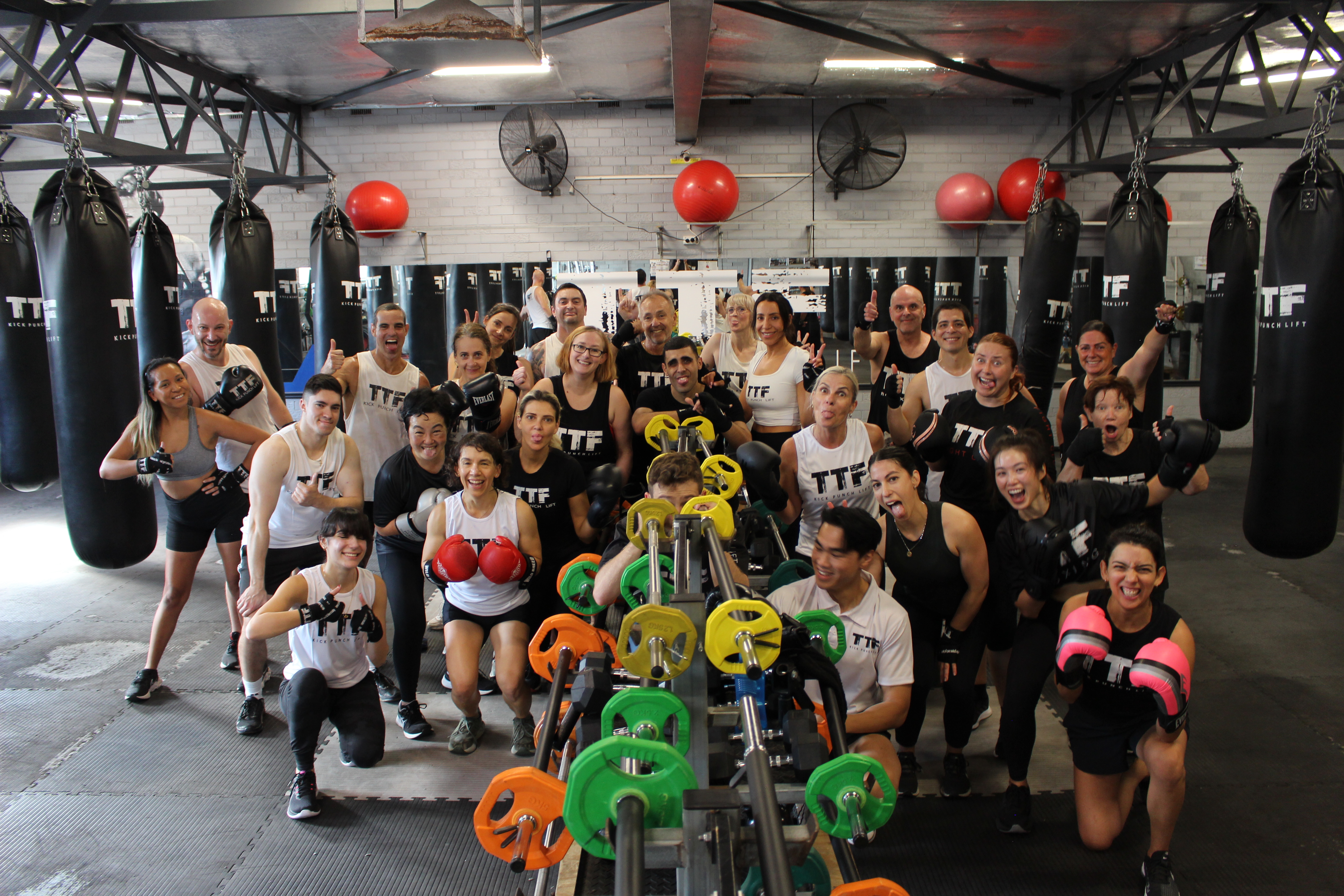 HIIT group training: why high-intensity intervals work better together Group of participants posing with weights and heavy bags after a HIIT class